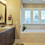Luxury sunny bathroom with granite countertops, shaker cabinets, energy efficient windows and travertine flooring. Notice the matching tub and sink.