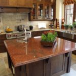 A very unusual red granite island adorns this modern designer kitchen on top of beautiful slate brown tiles